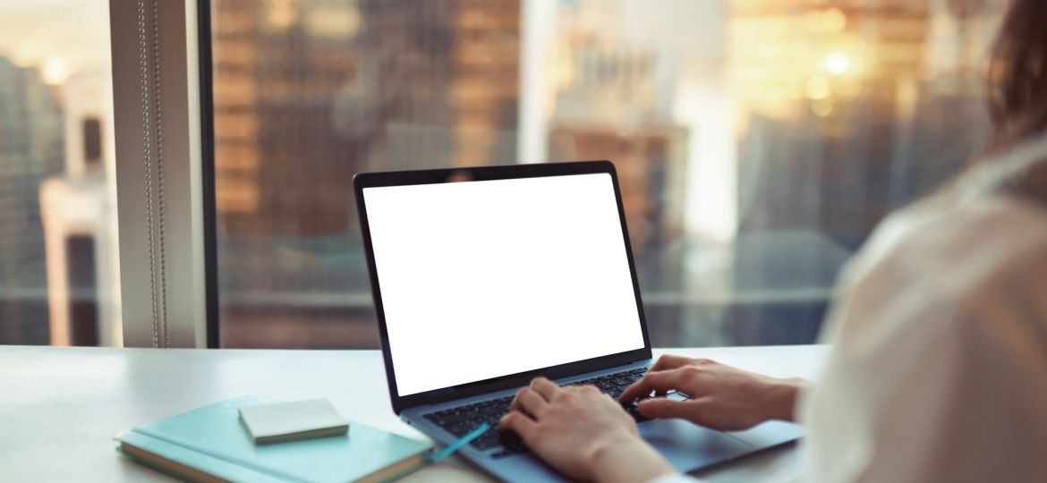 Business woman working on laptop computer in office. White mock up screen